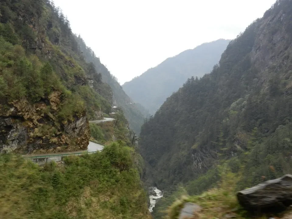 Paesaggio montano profondo con valli fluviali e vegetazione lussureggiante in Nepal e Tibet.