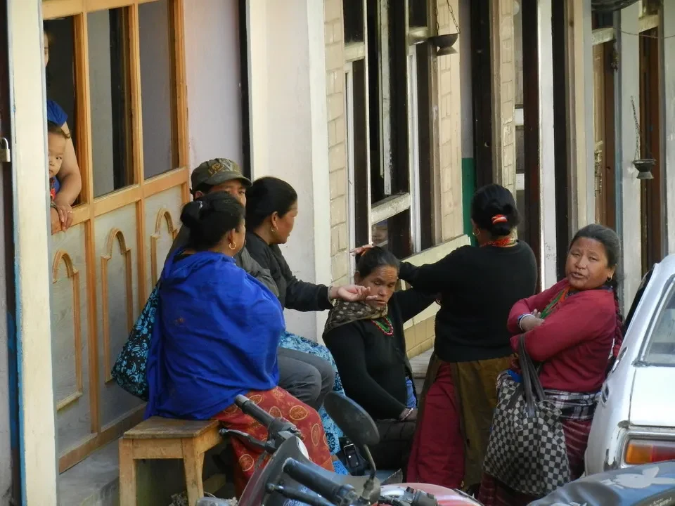 Gruppo di persone sedute davanti a una casa in Nepal o Tibet.