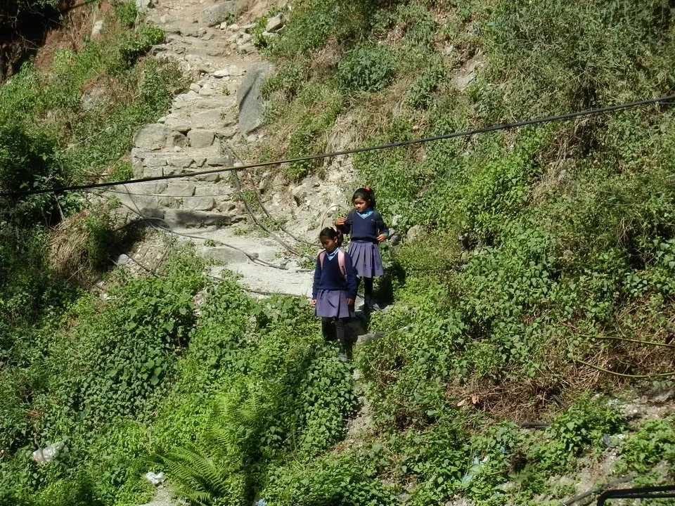 Due bambini camminano su un sentiero roccioso in una zona montuosa.