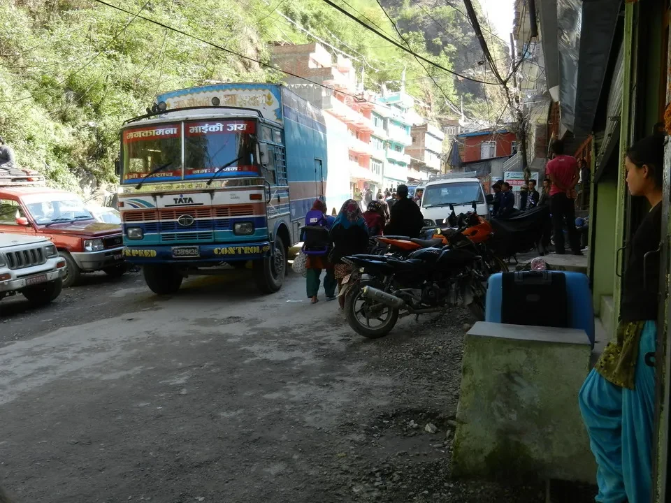 Autobus e motocicli sono parcheggiati lungo una strada stretta tra le montagne.