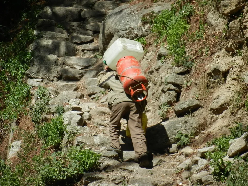 Un uomo trasporta acqua su una ripida strada di montagna in Nepal o Tibet.
