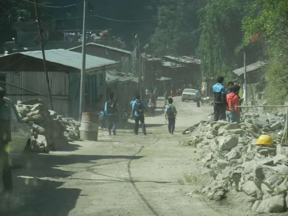 Un gruppo di persone cammina lungo una strada sterrata in un ambiente montano.