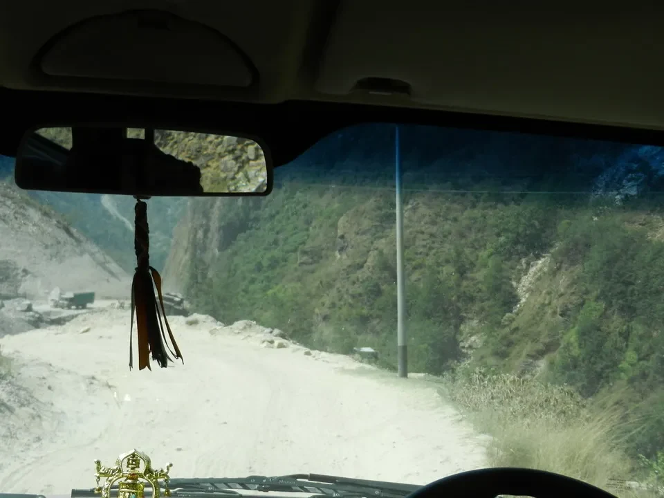 Un paesaggio montano con una strada sterrata attraversa colline verdi.