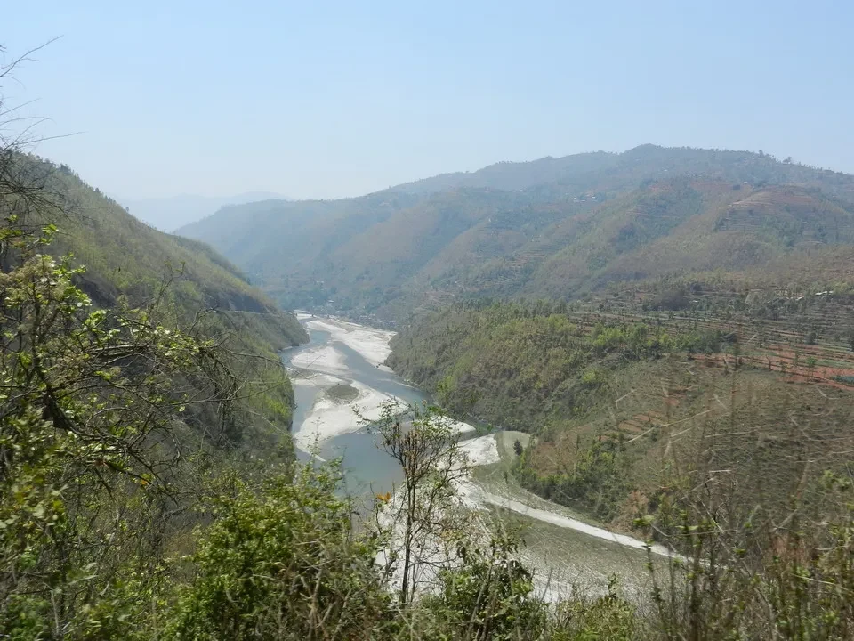 Paesaggio montano con un fiume che scorre attraverso una valle verdeggiante in Nepal e Tibet.