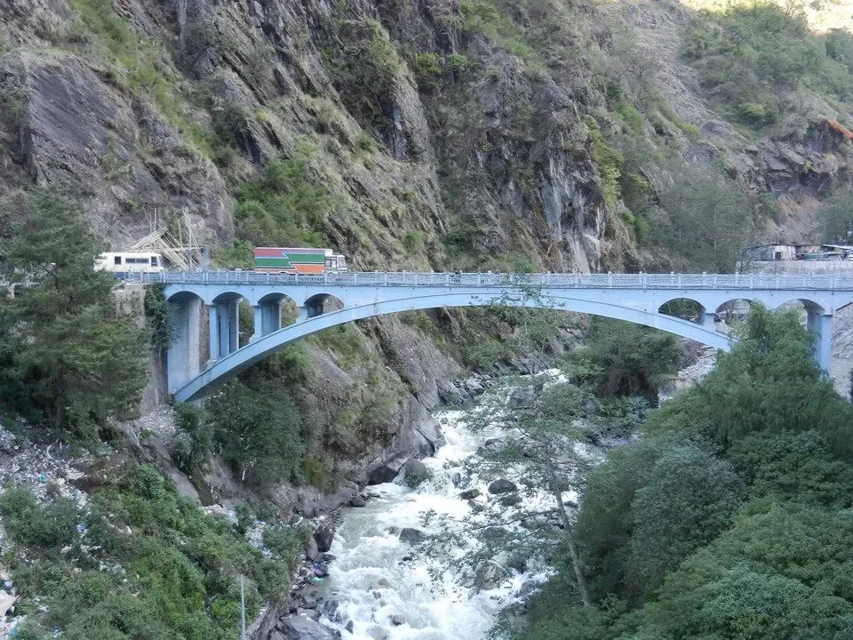 Un ponte in pietra attraversa un fiume selvaggio tra le montagne.