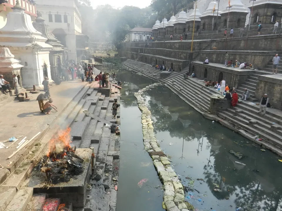 Architettura antica lungo un canale con fuoco rituale.