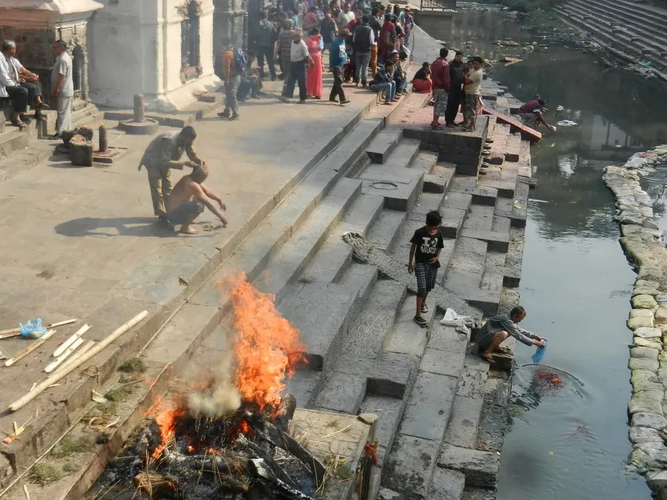Persone si radunano lungo un fiume in un contesto storico di Nepal o Tibet.
