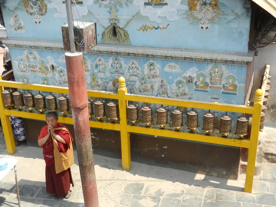 Un uomo in abiti monastici si trova davanti a un muro decorato di un monastero in Nepal o Tibet.