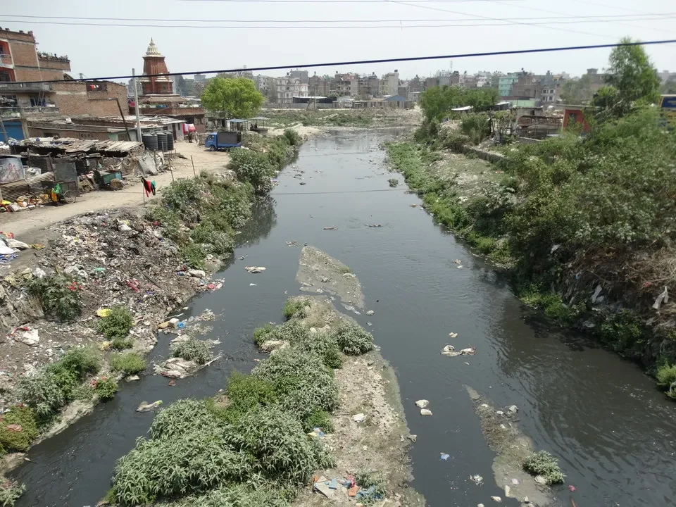Un fiume sporco scorre attraverso un insediamento vicino a Kathmandu.