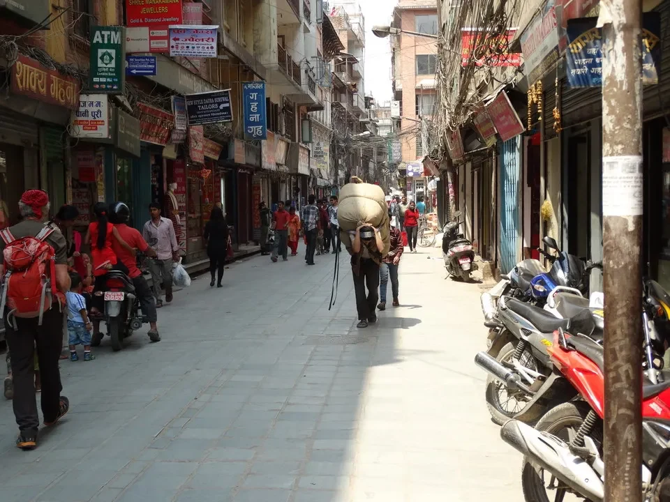 Una strada pedonale affollata a Kathmandu con negozi lungo i lati.