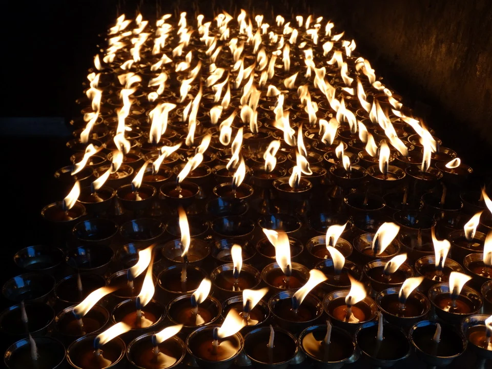 Candele accese formano una luce calda su una vasta disposizione di candele.