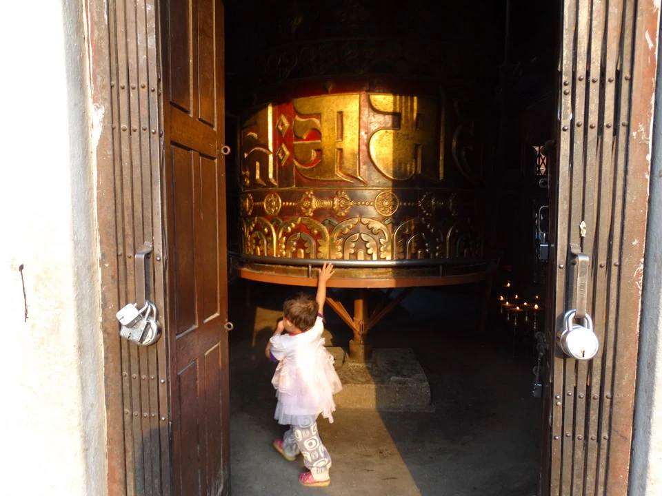 Un bambino guarda un grande oggetto dorato all'interno di una porta in legno.