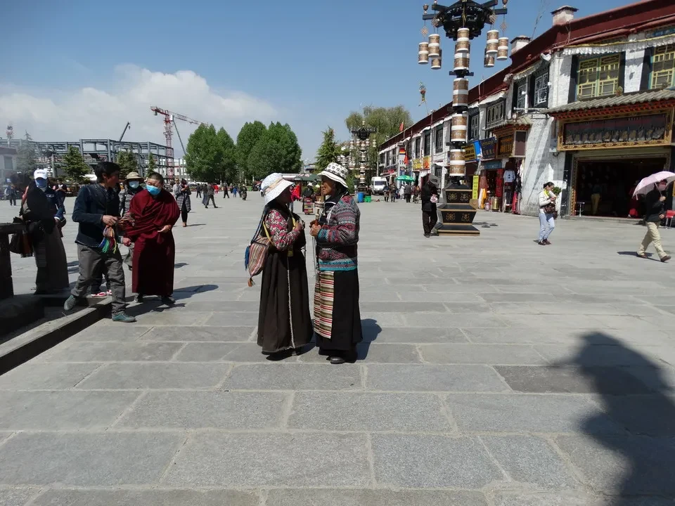 Persone in abiti tradizionali passeggiano su una piazza in Tibet vicino a Kathmandu.