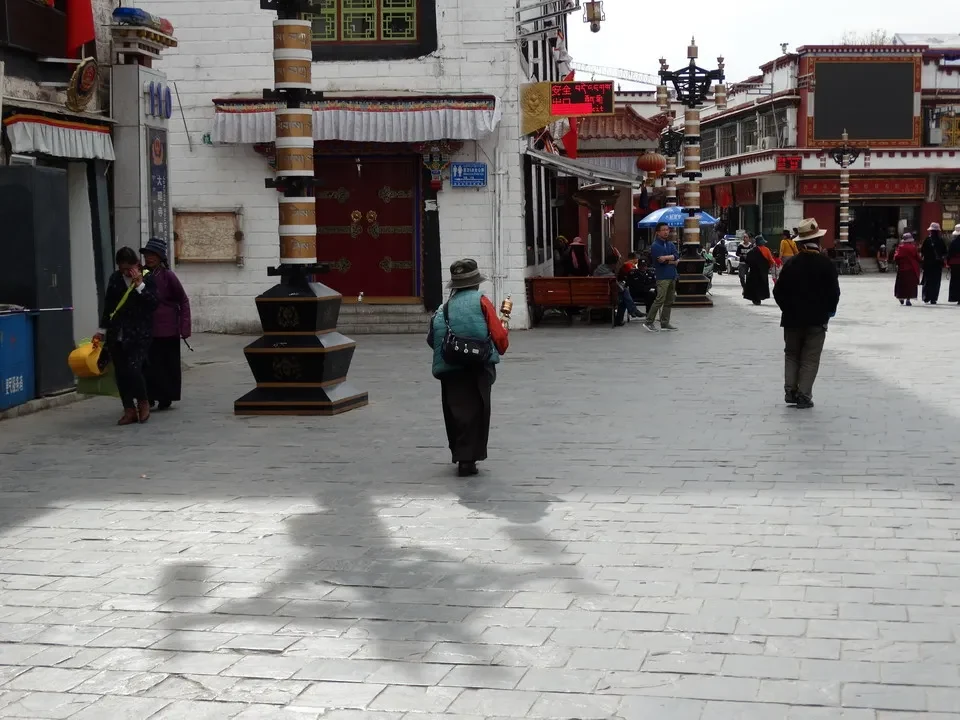 Una piazza aperta con edifici tradizionali in stile tibetano e persone che passeggiano.