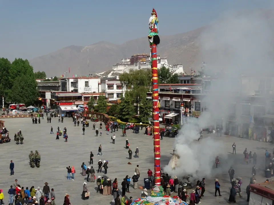 Una colonna decorata con bandiere si erge sopra una piazza affollata in Tibet vicino a Kathmandu.