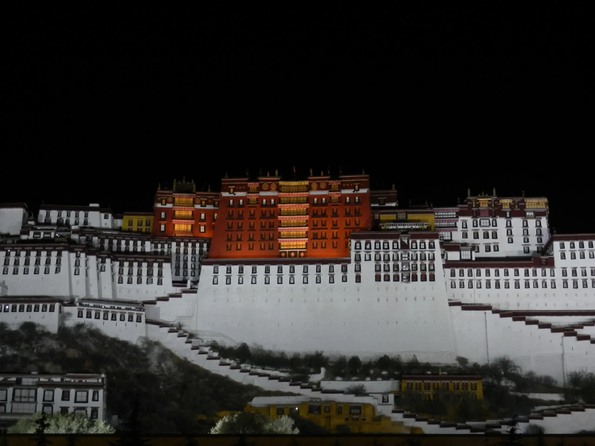Il Palazzo del Potala a Lhasa illuminato di notte con vista sul Kailash.