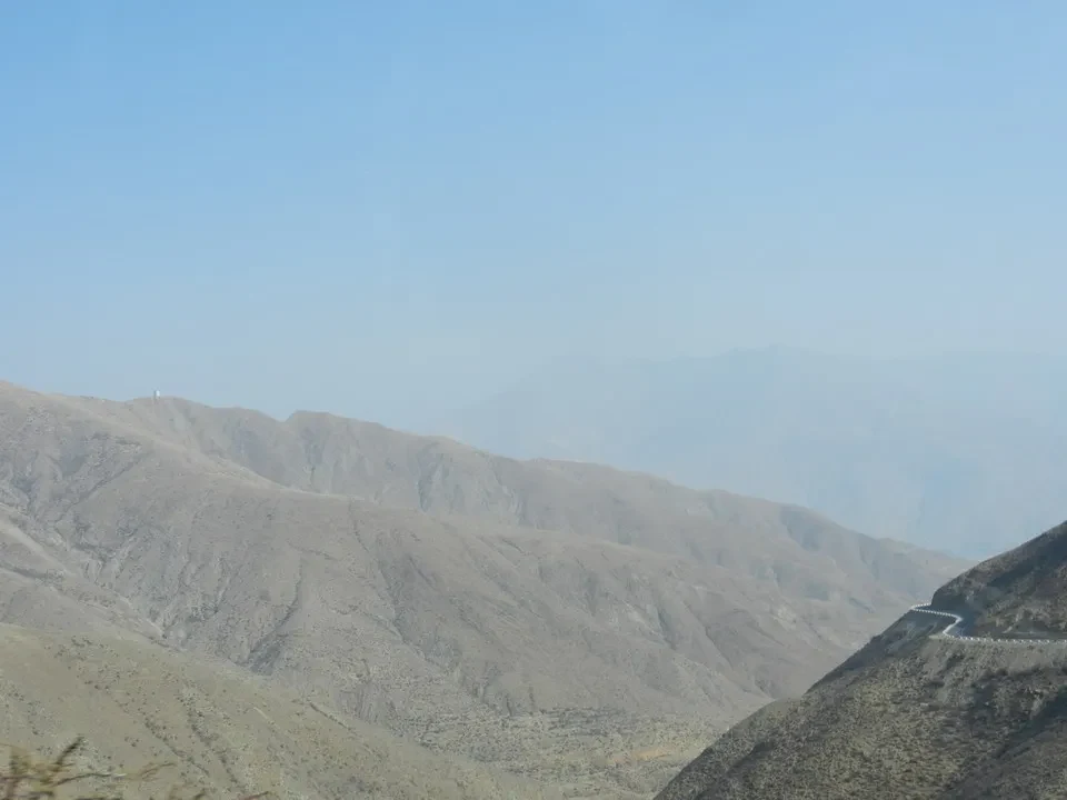 Montagne aride e ondulate si estendono sotto un cielo sereno.