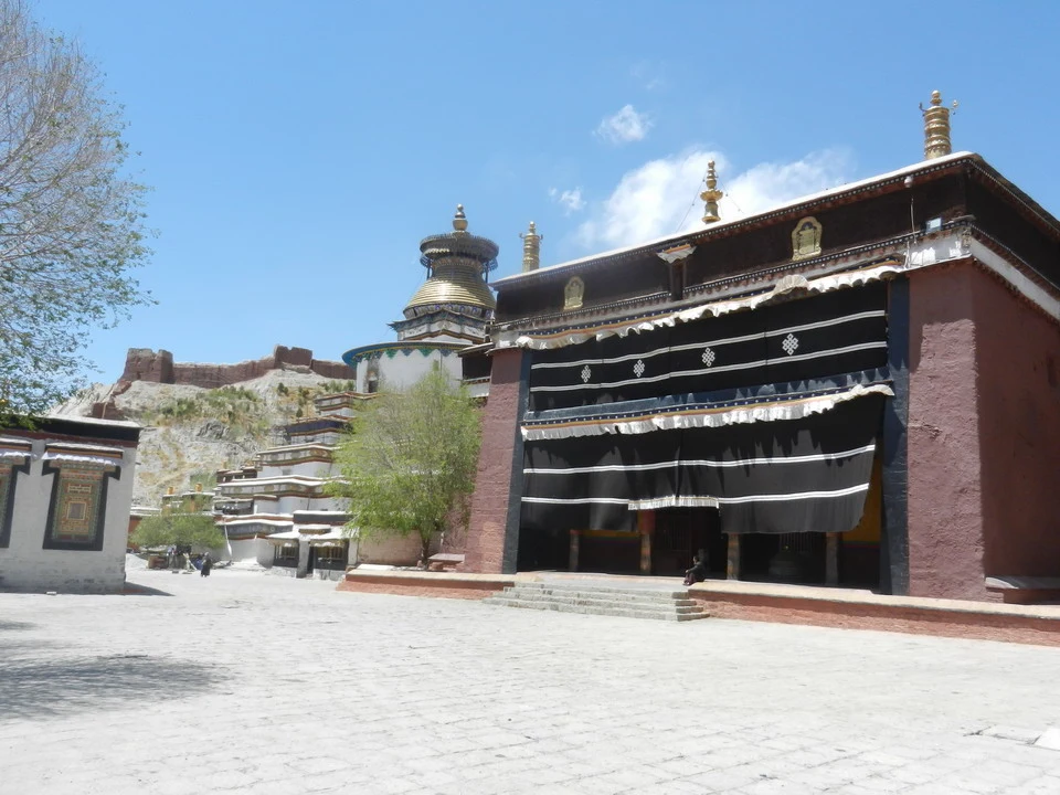 Vista di un monastero tibetano con una piazza aperta sotto un cielo azzurro.