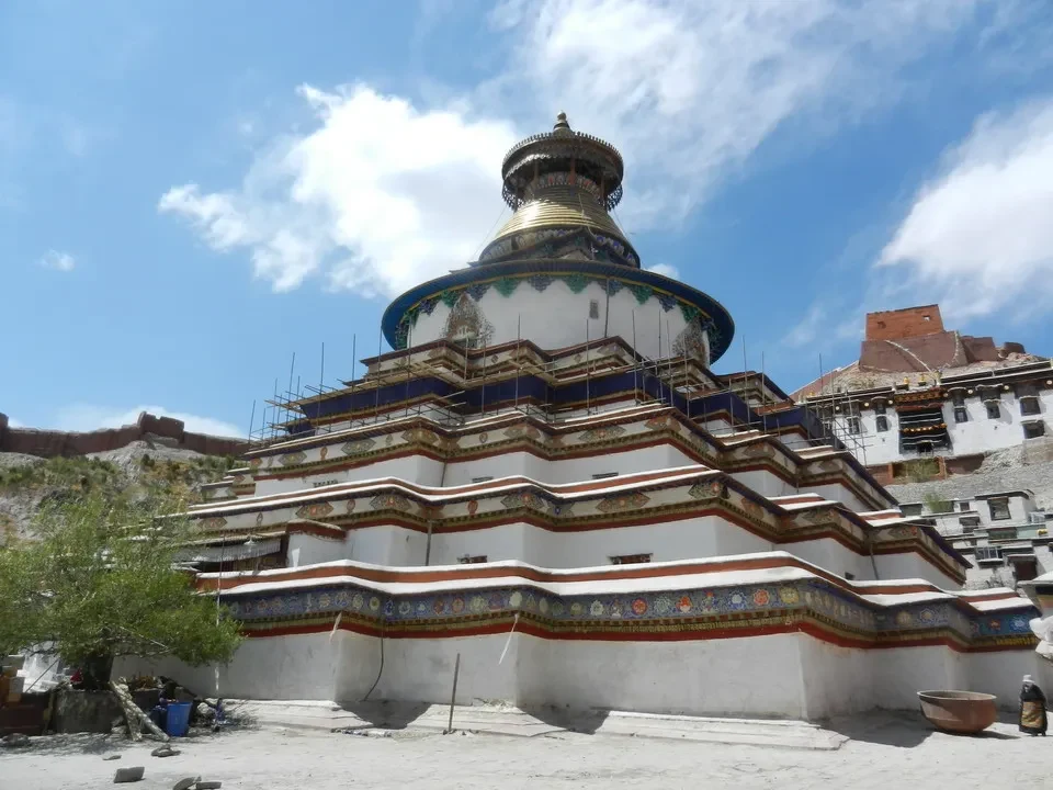 Tempio buddista in Tibet con guglie dorate sotto un cielo azzurro.