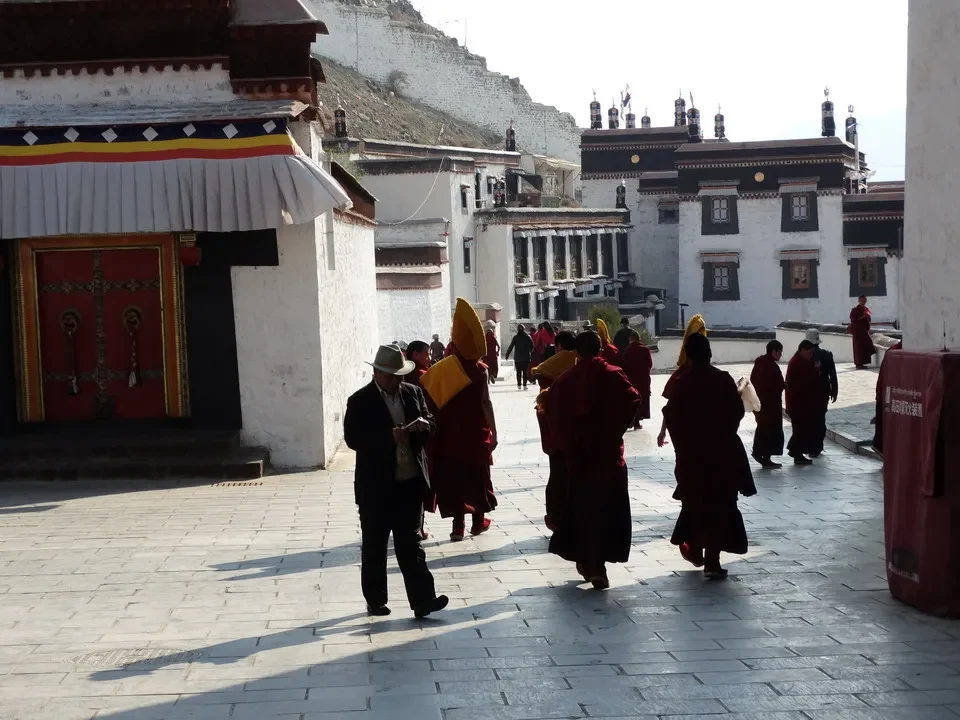Persone camminano lungo una strada in un monastero tibetano vicino a Kathmandu.
