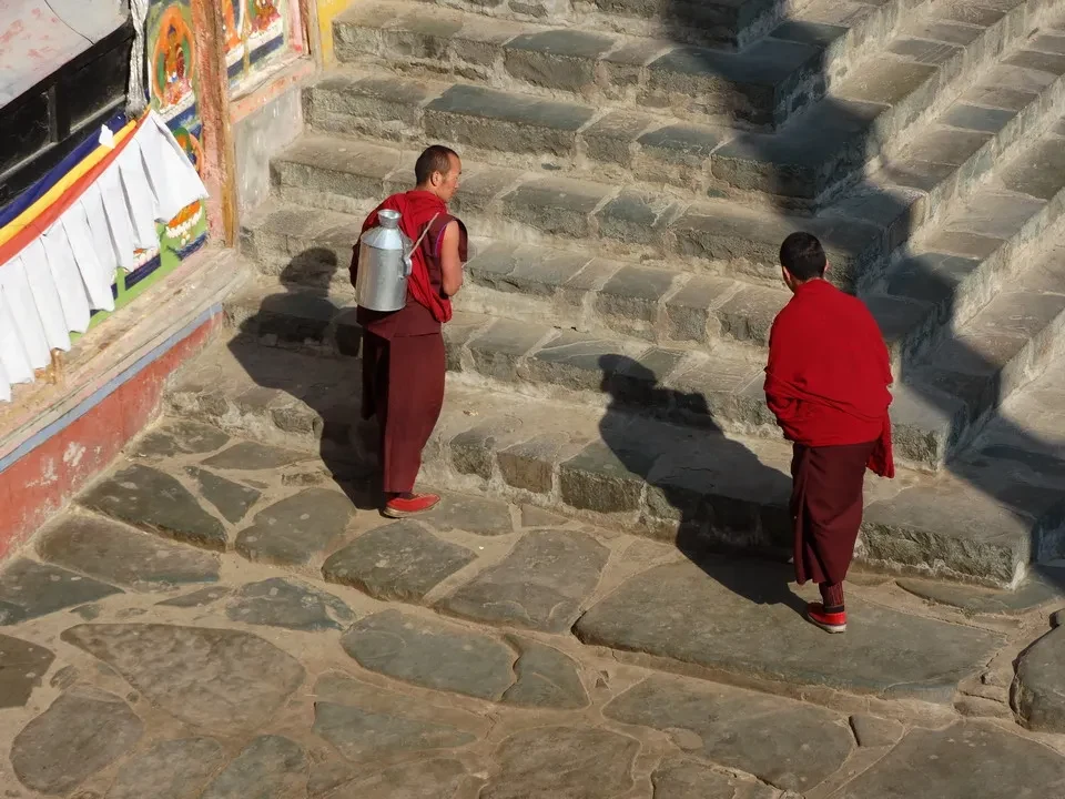 Due uomini in abiti rossi camminano su gradini di pietra.