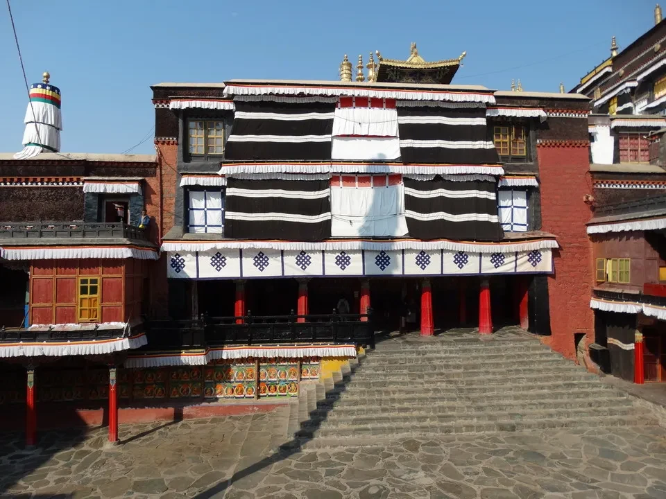 Vista di un monastero tibetano con architettura tradizionale in una piazza aperta.