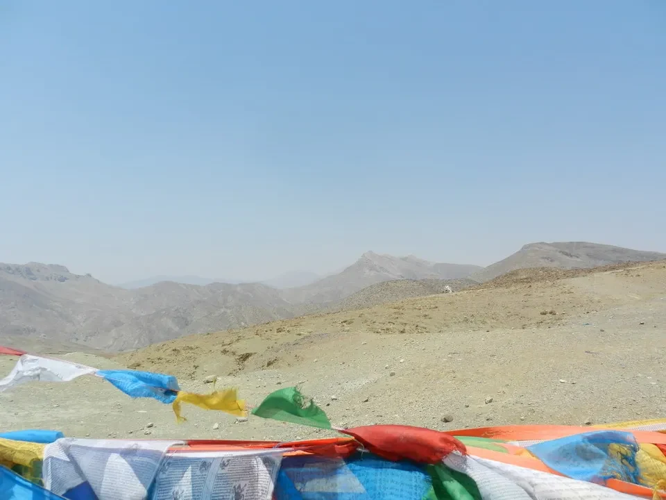 Paesaggio montano arido con drappi colorati in primo piano.