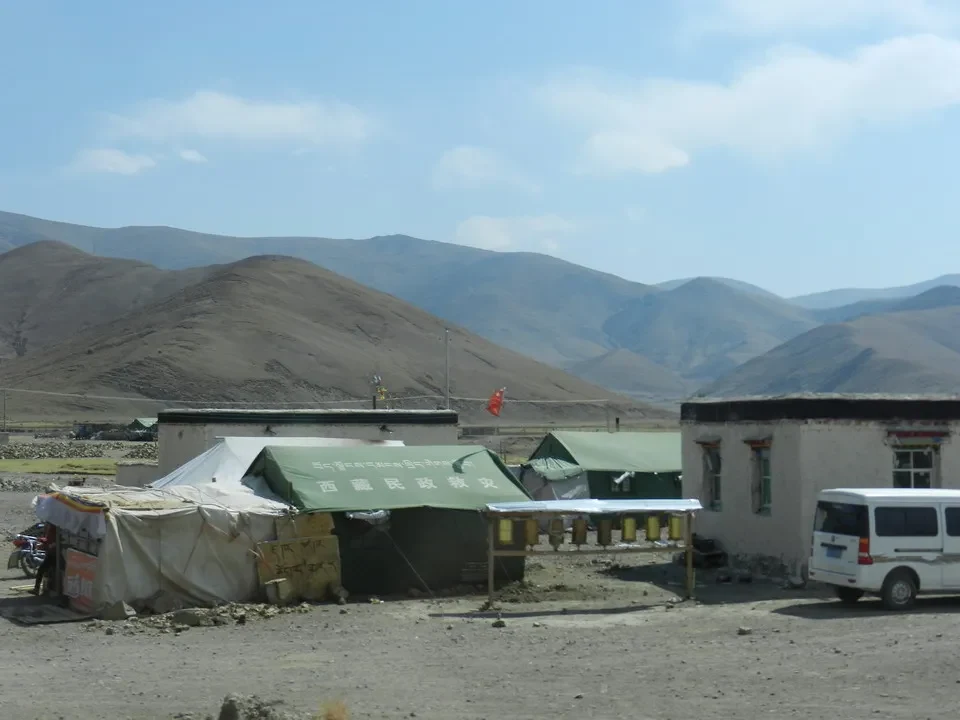 Paesaggio montano del Tibet con strutture abitative in primo piano.