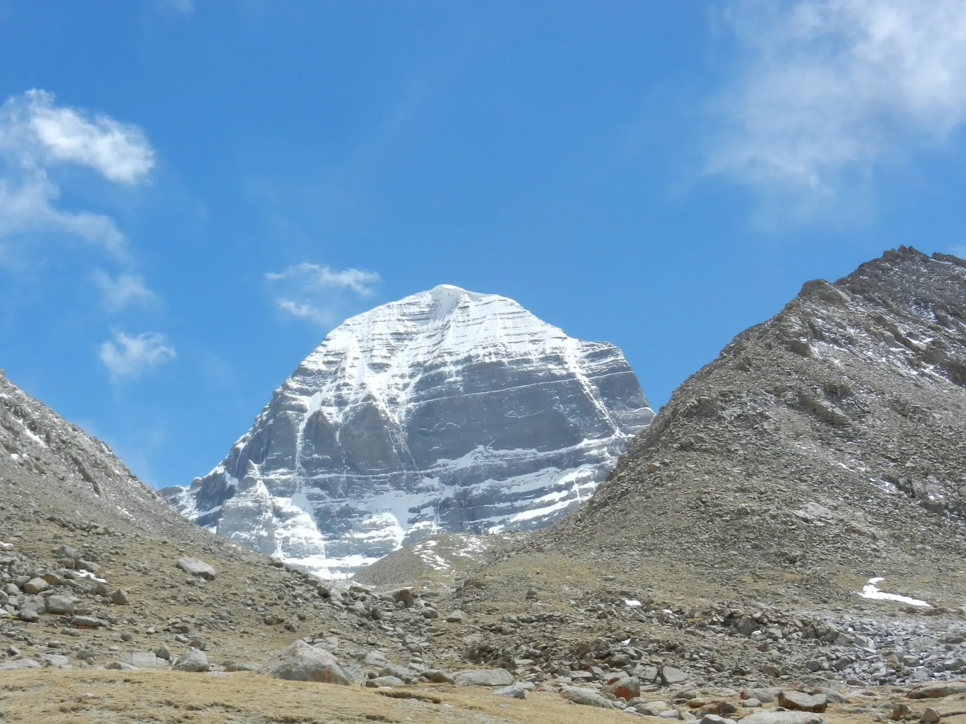 Paesaggio montano con il Monte Kailash visibile sotto un cielo azzurro.