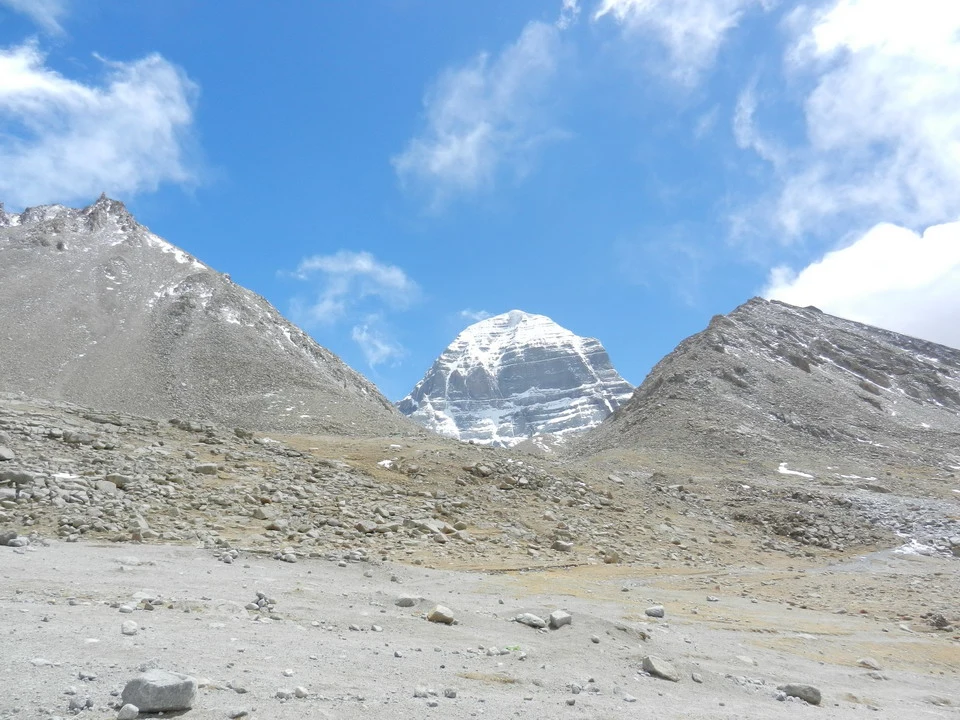 Le montagne del Tibet e del Kailash si stagliano sotto un cielo azzurro con nuvole bianche.