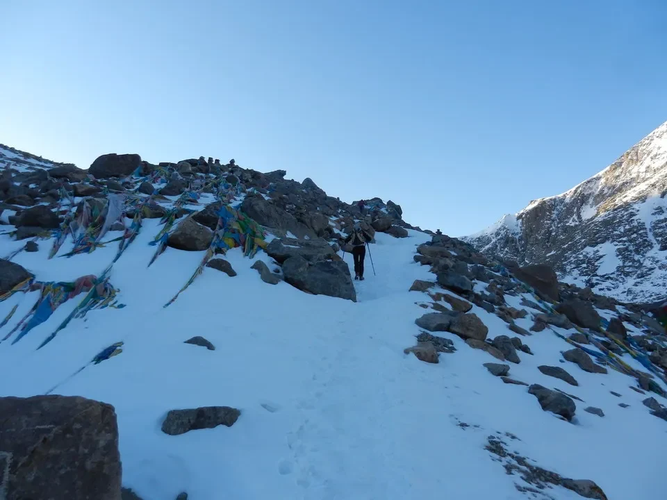 Un sentiero innevato conduce attraverso un paesaggio montano roccioso verso le vette del Kailash.