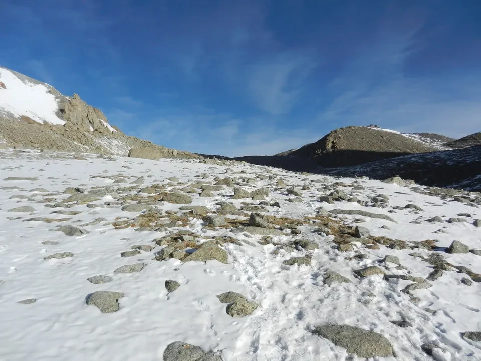 Paesaggio alpino con montagne innevate sotto un cielo azzurro.