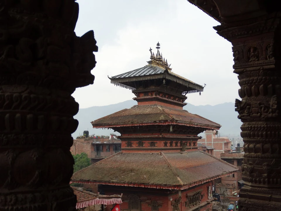 Vista di un antico edificio del Nepal incorniciata da dettagli architettonici tradizionali.