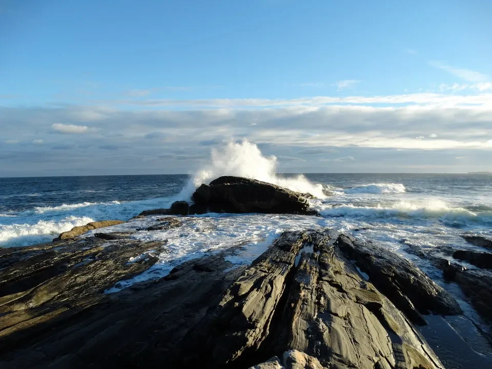 Roccia scura bagnata onde frangono sulla costa della Nuova Inghilterra.