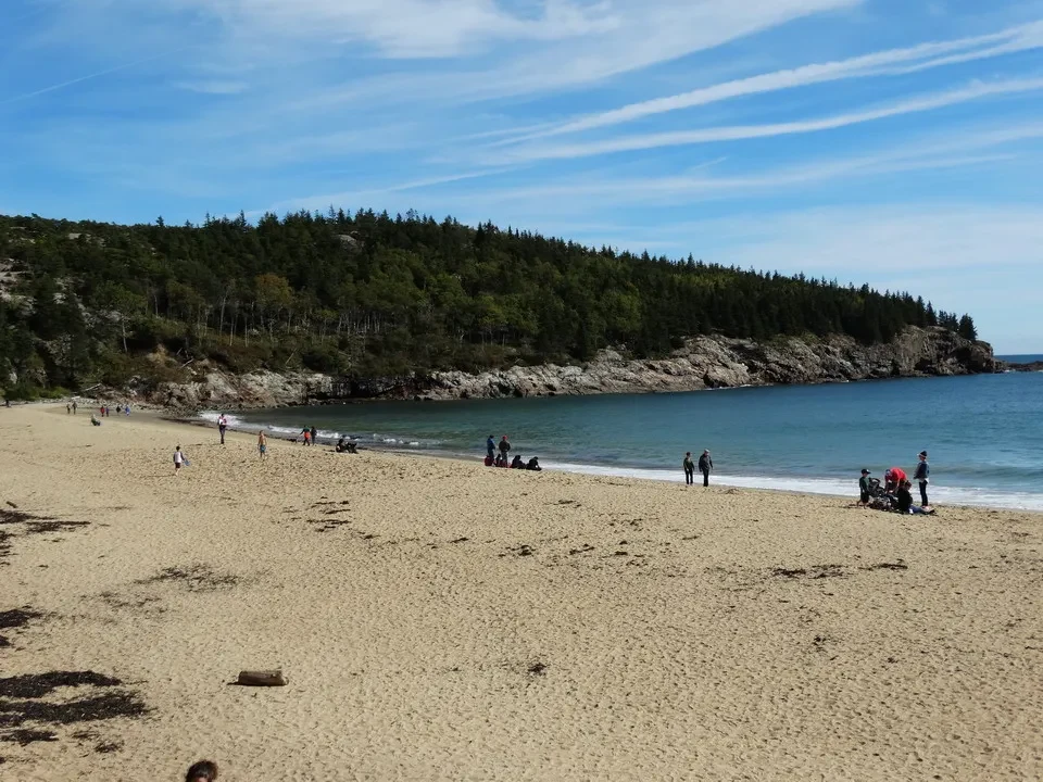 Una spiaggia sabbiosa e rocciosa si estende lungo la costa con il mare blu sullo sfondo.