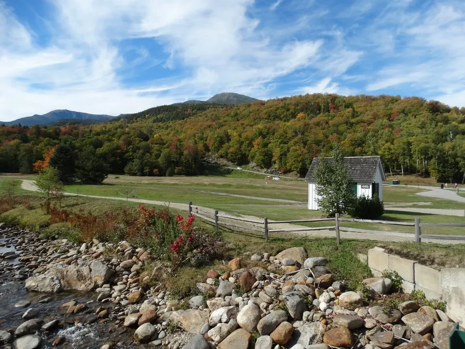 Paesaggio autunnale della regione del Massachusetts con una valle boscosa e un fiume in primo piano.