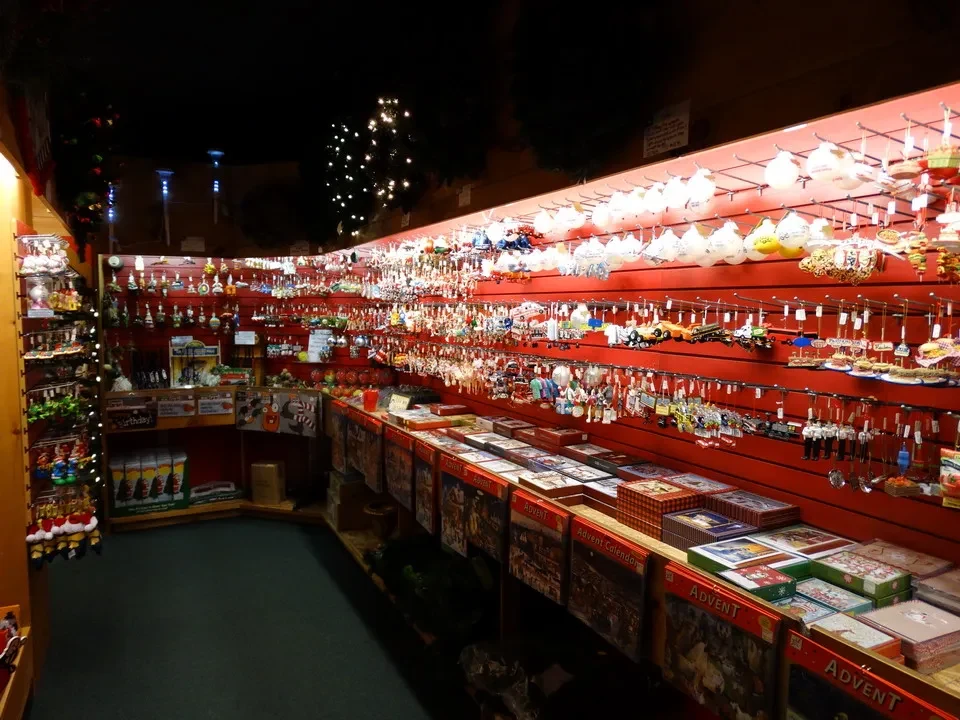 Una galleria di negozi decorati con oggetti festivi si estende lungo una parete rossa.