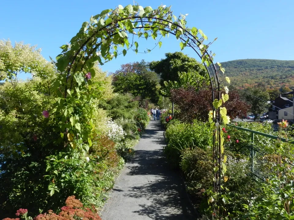 Un ponte floreale attraversa un sentiero verde in una zona rurale della New England.