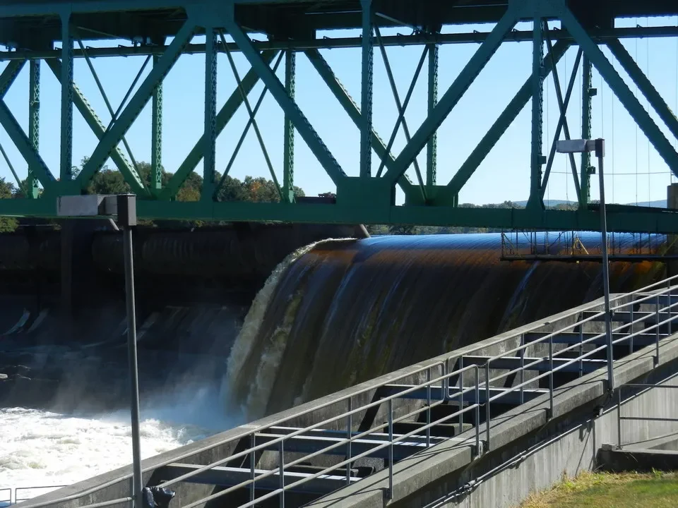 Una cascata d'acqua scorre attraverso una struttura in ferro battuto che attraversa il fiume.