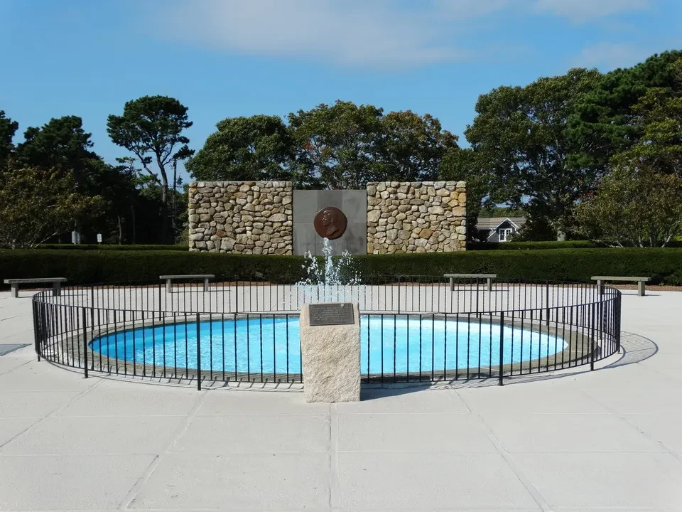 Una fontana circolare con una base in pietra si trova in un parco verde.