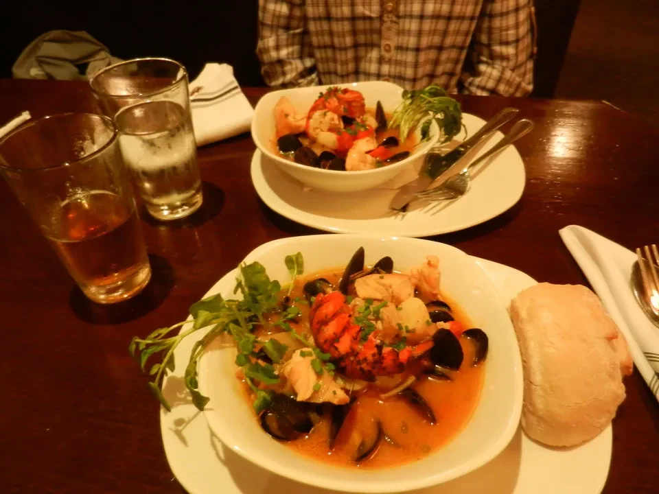 Un tavolo in un ristorante mostra piatti di pesce e pane.