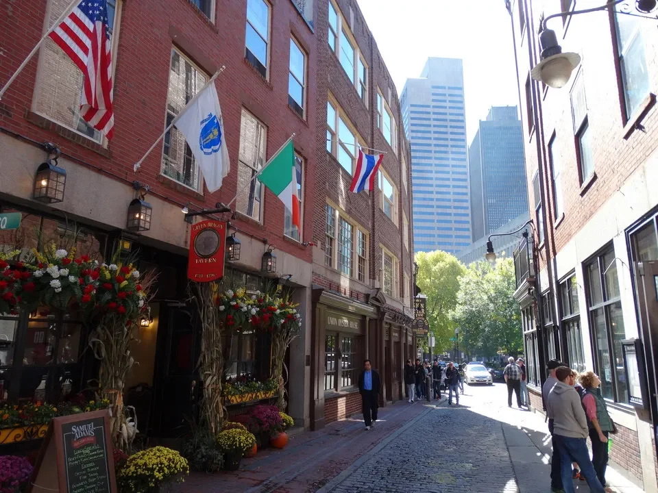 Una galleria fotografica di una strada pedonale con edifici storici e bandiere in New England.