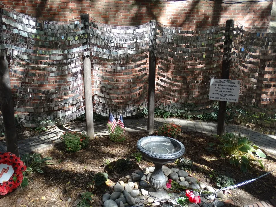 Muro di mattoni commemorativo con nomi incisi in una parete.
