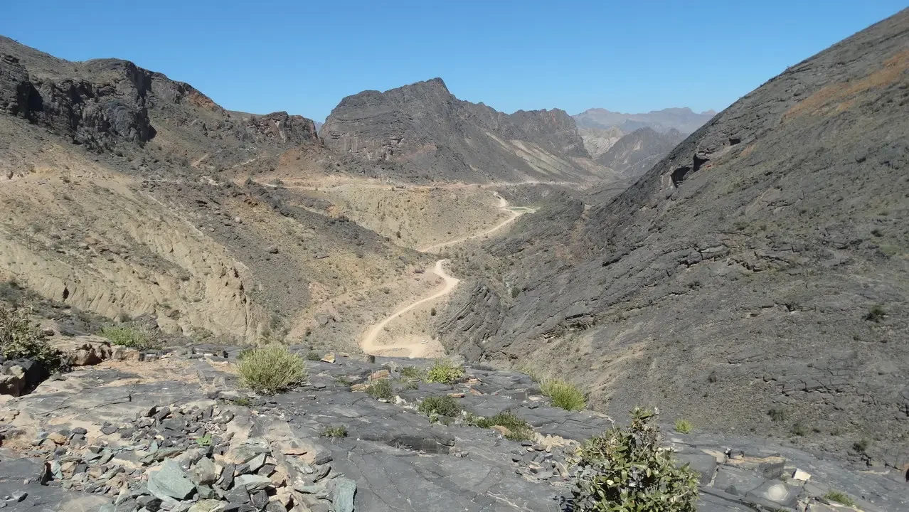 Un sentiero sinuoso attraversa un canyon roccioso nel deserto dell'Oman.