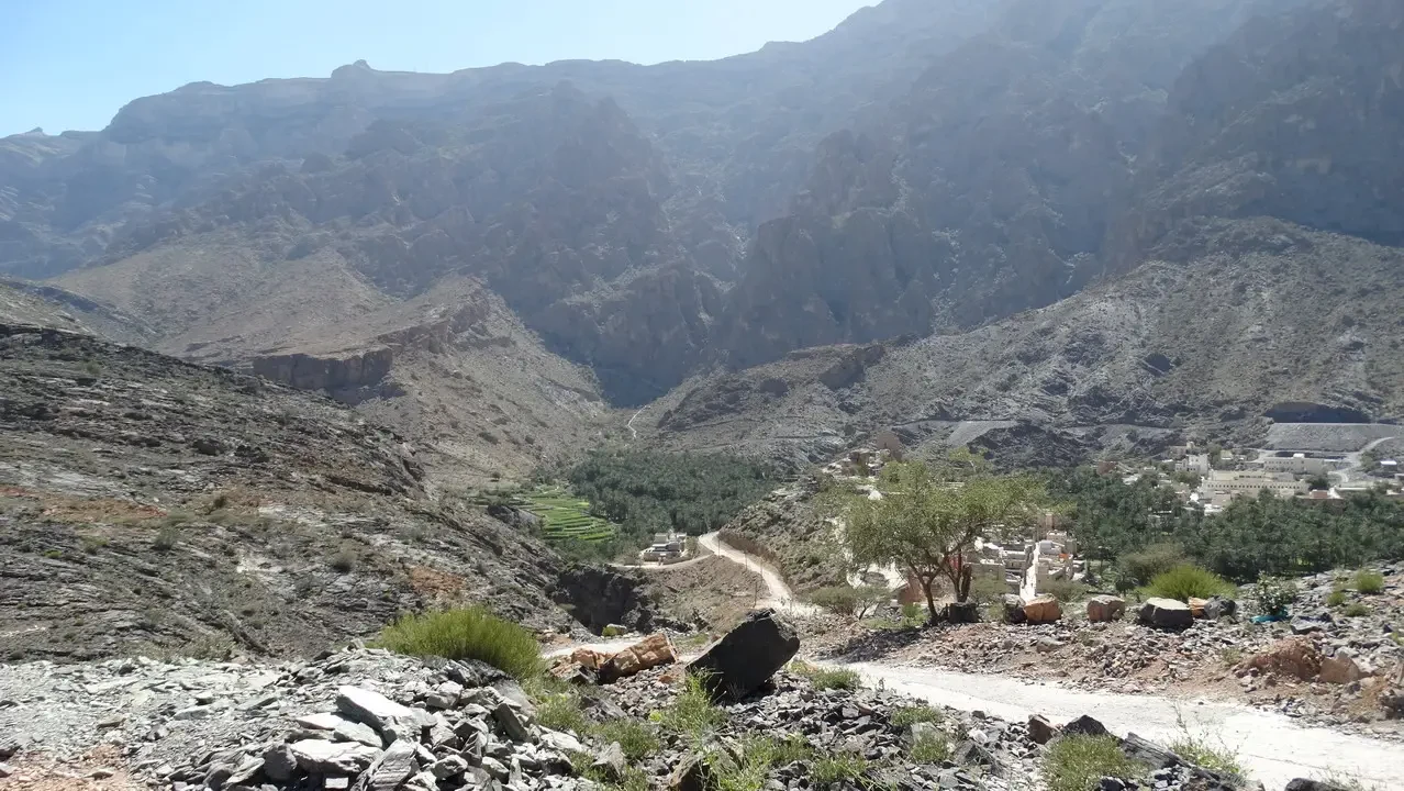 Paesaggio montano arido con un sentiero che attraversa una gola nella regione dell'Oman o degli Emirati Arabi Uniti.