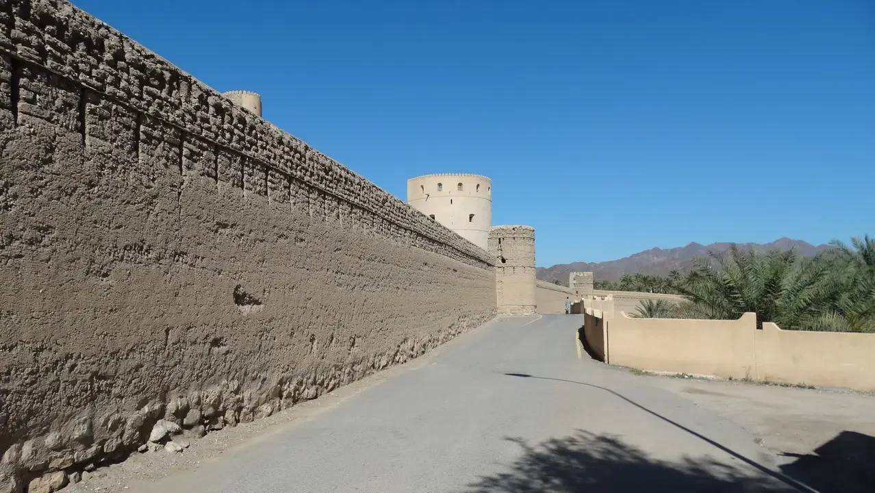 Mura di cinta antica con torri in pietra sotto il cielo blu.