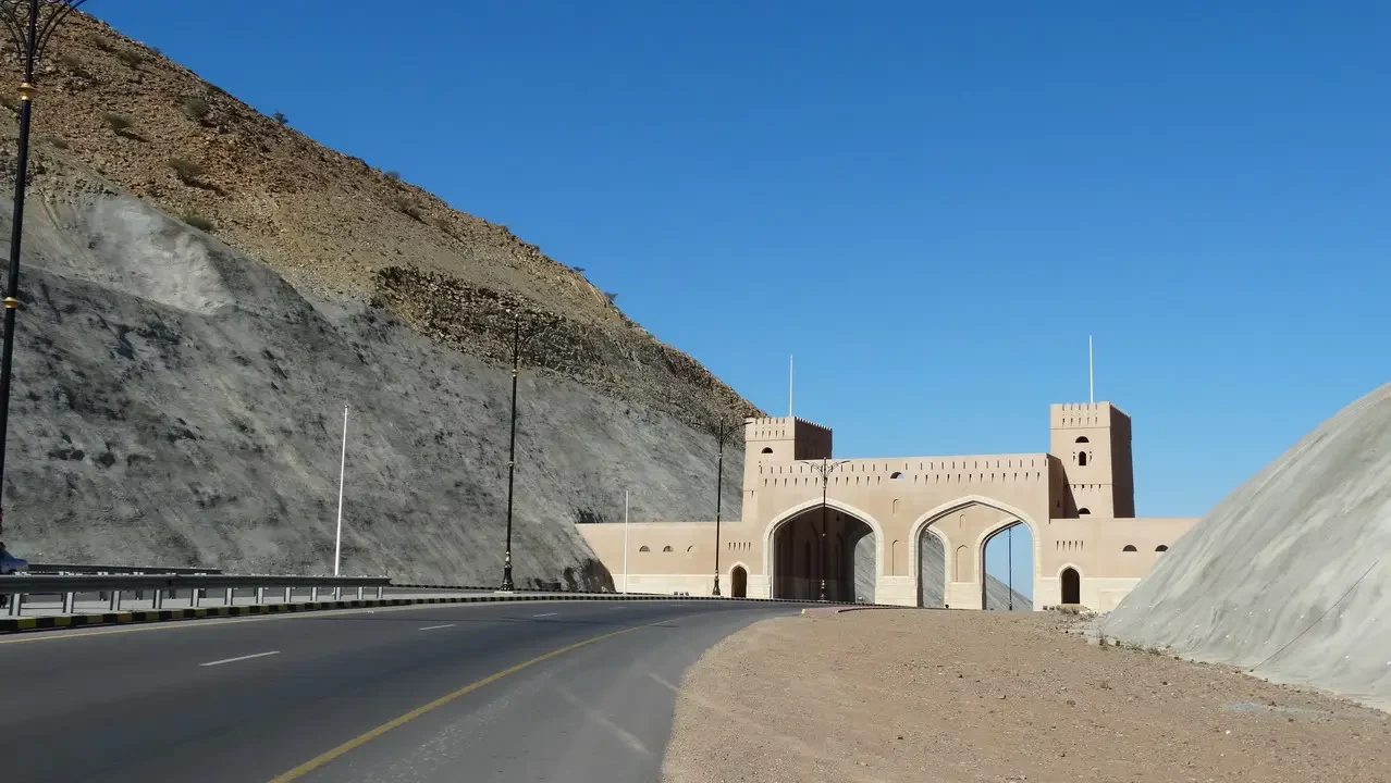 Portale architettonico in pietra lungo una strada costiera in Oman.