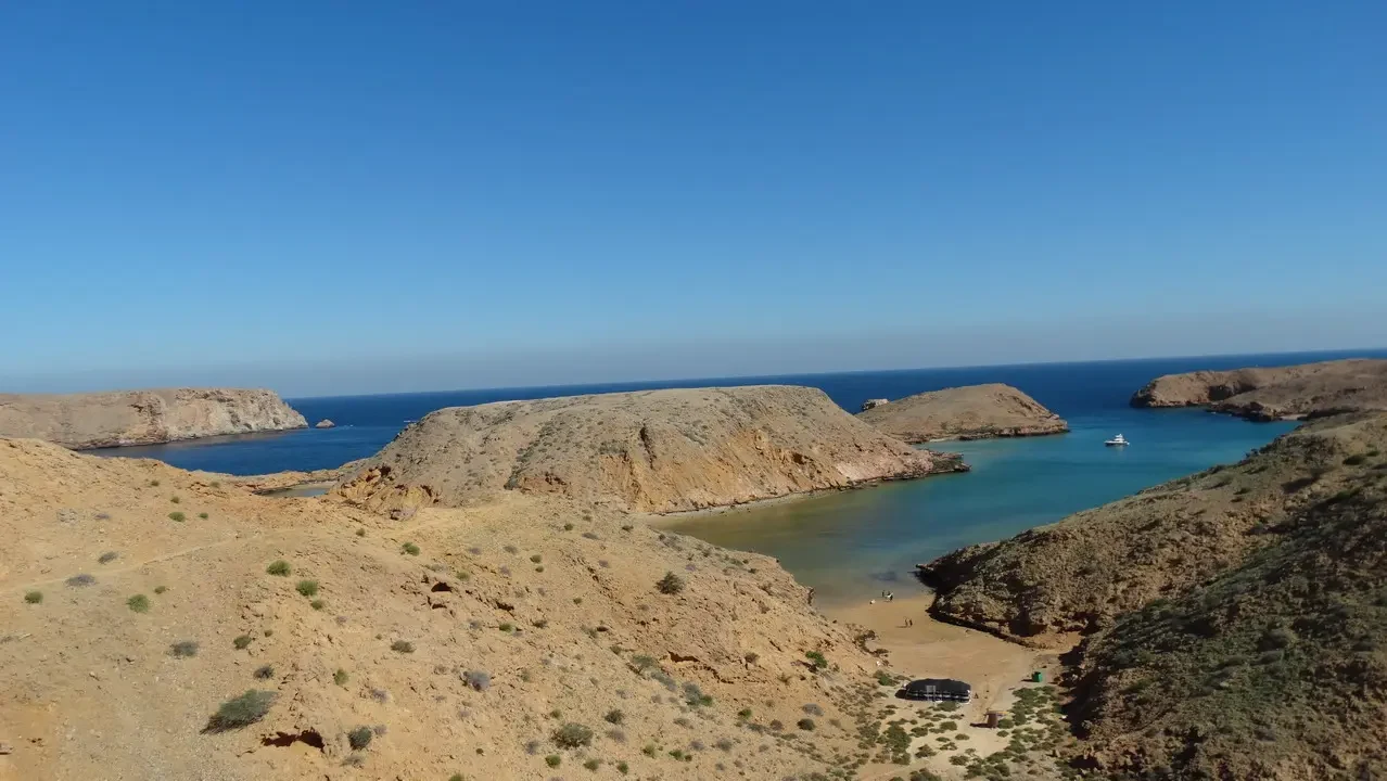 Paesaggio costiero arido con scogliere rocciose e acqua turchese sotto un cielo limpido. Paesaggio costiero arido con scogliere rocciose e acqua turchese sotto un cielo limpido.