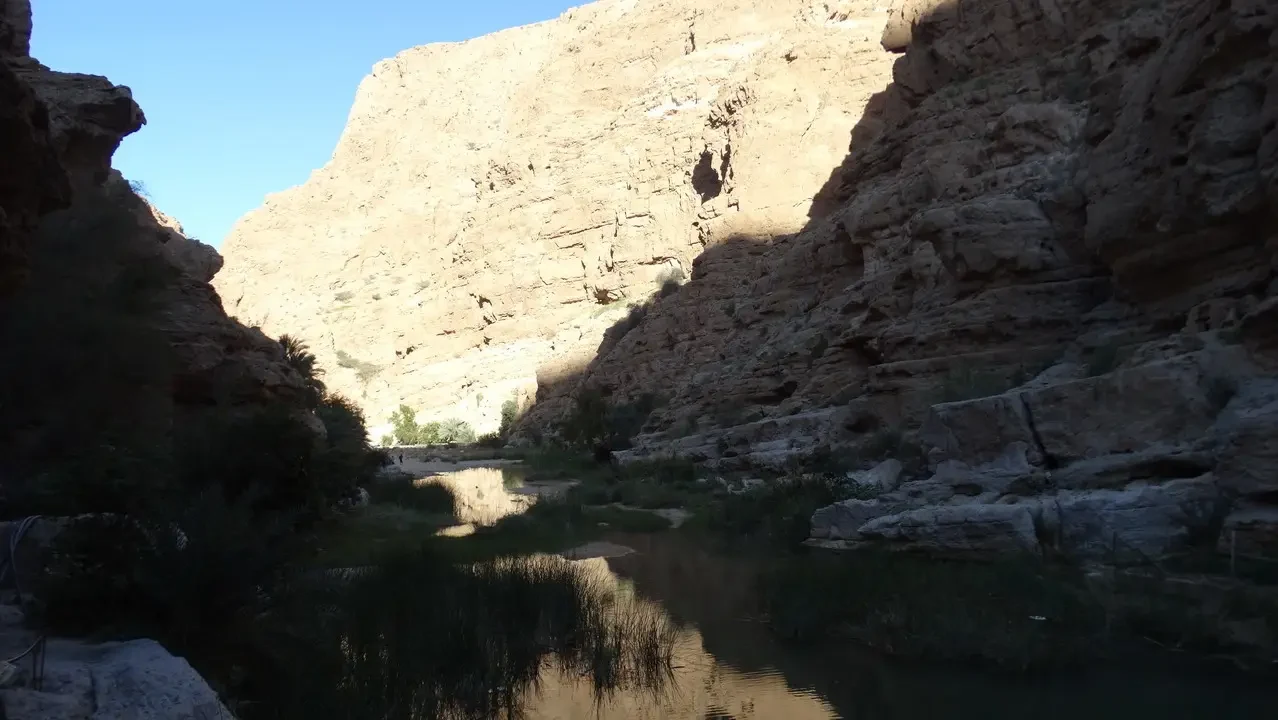Un fiume scorre attraverso un canyon roccioso sotto la luce del sole.
