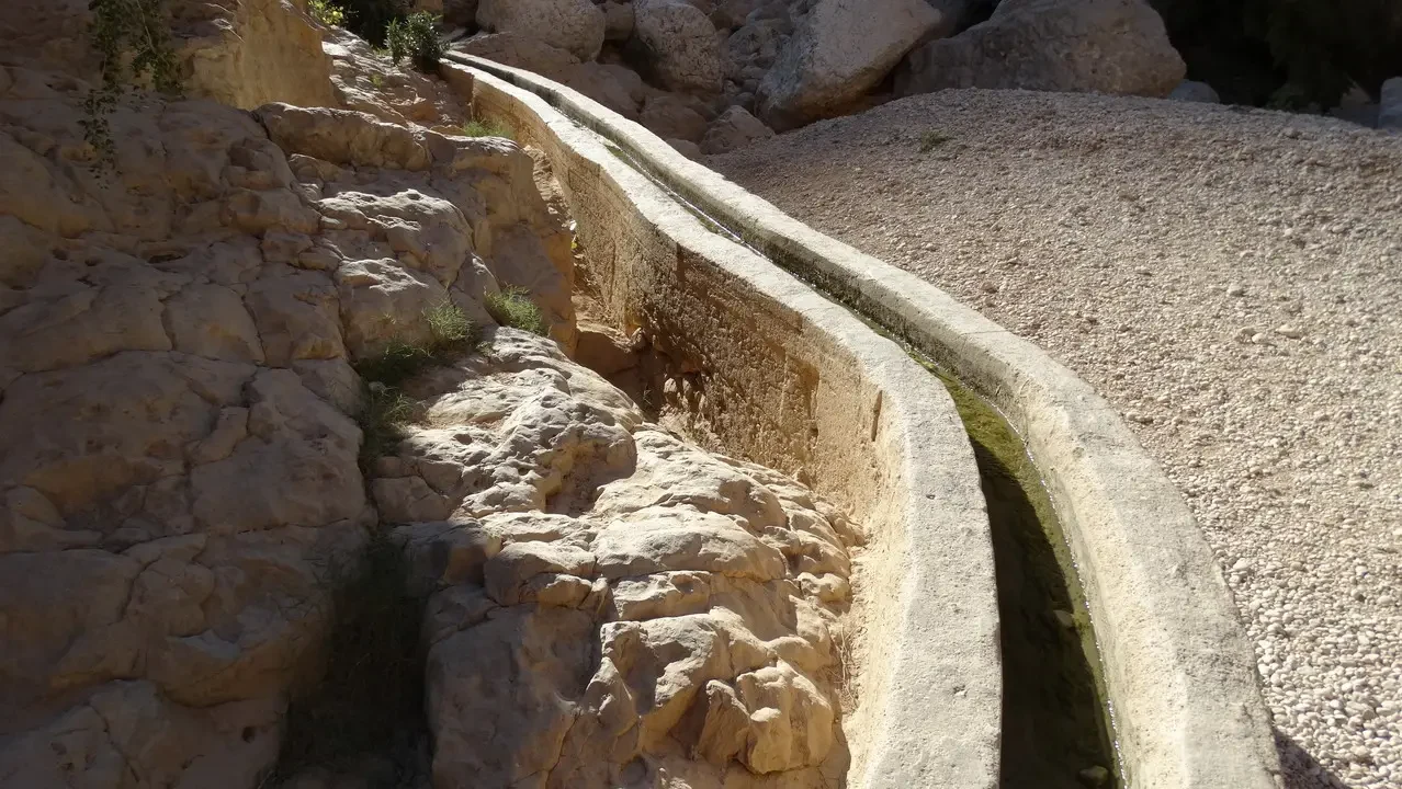Un sentiero stretto costeggia una gola rocciosa in un paesaggio arido.